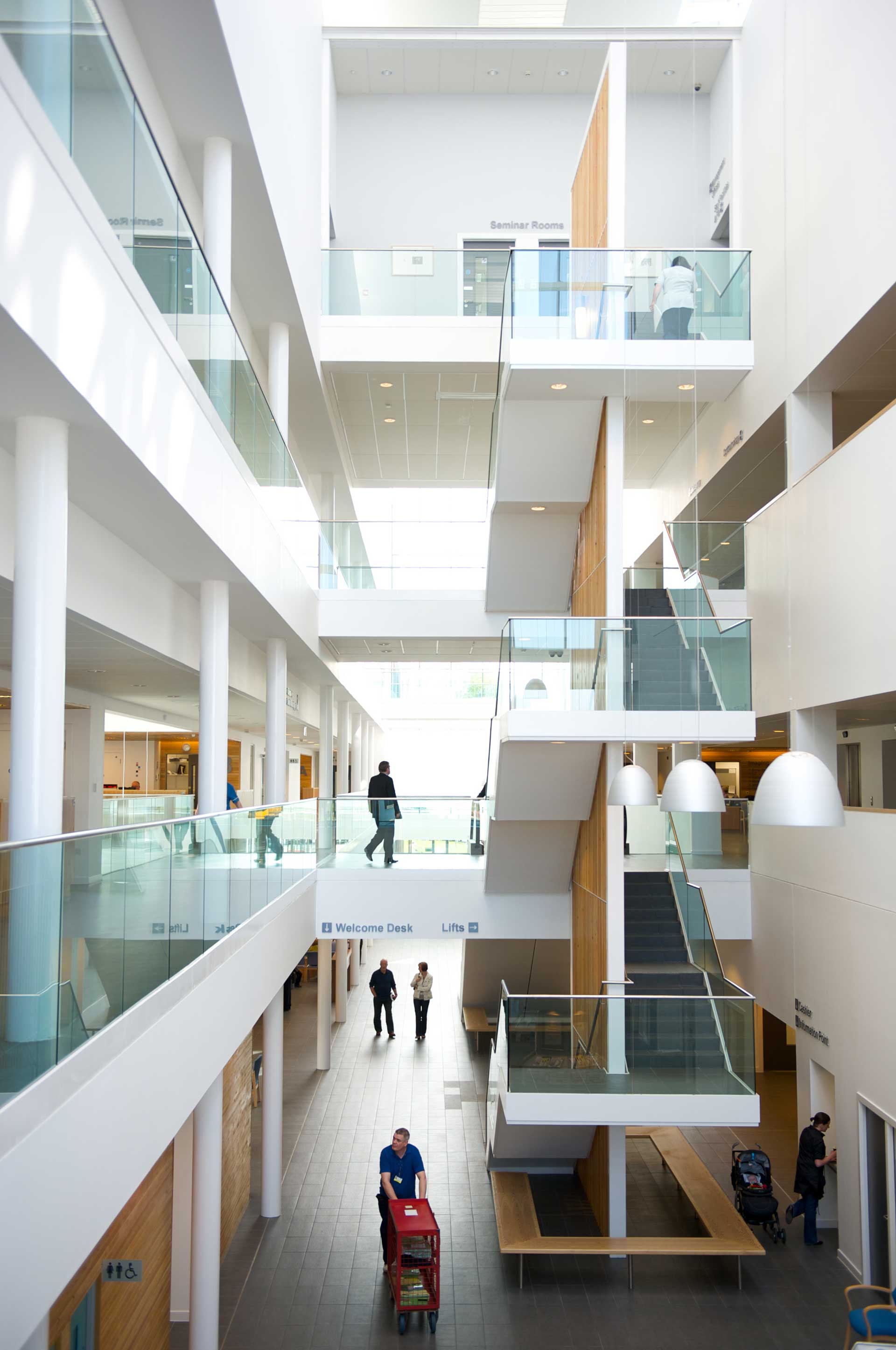 A photograph of a bright atrium space in a hospital where you can see people on several levels and walking stairs between the floors