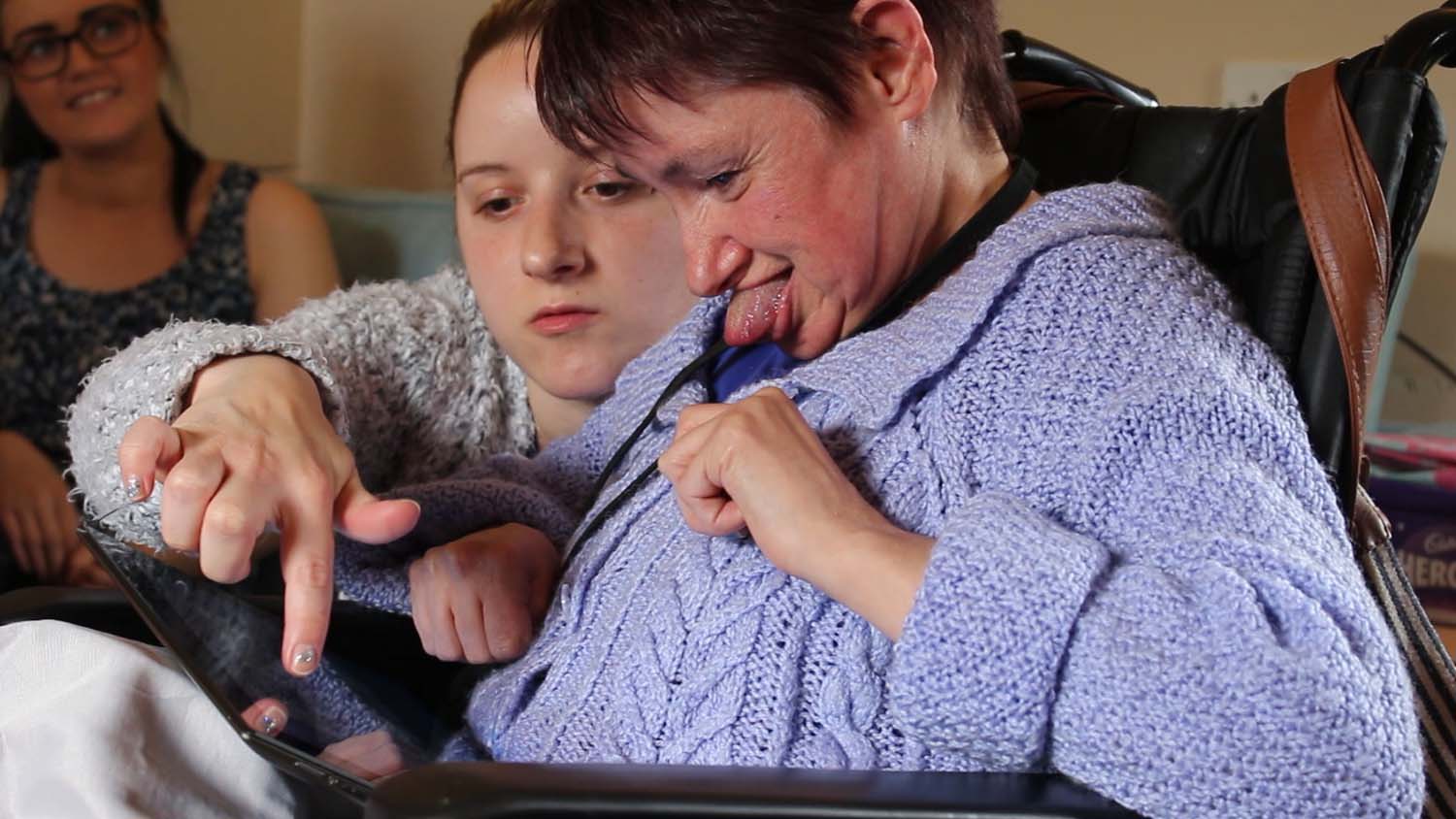 A carer shows a disabled woman from Blackwood Homes how to use a tablet.