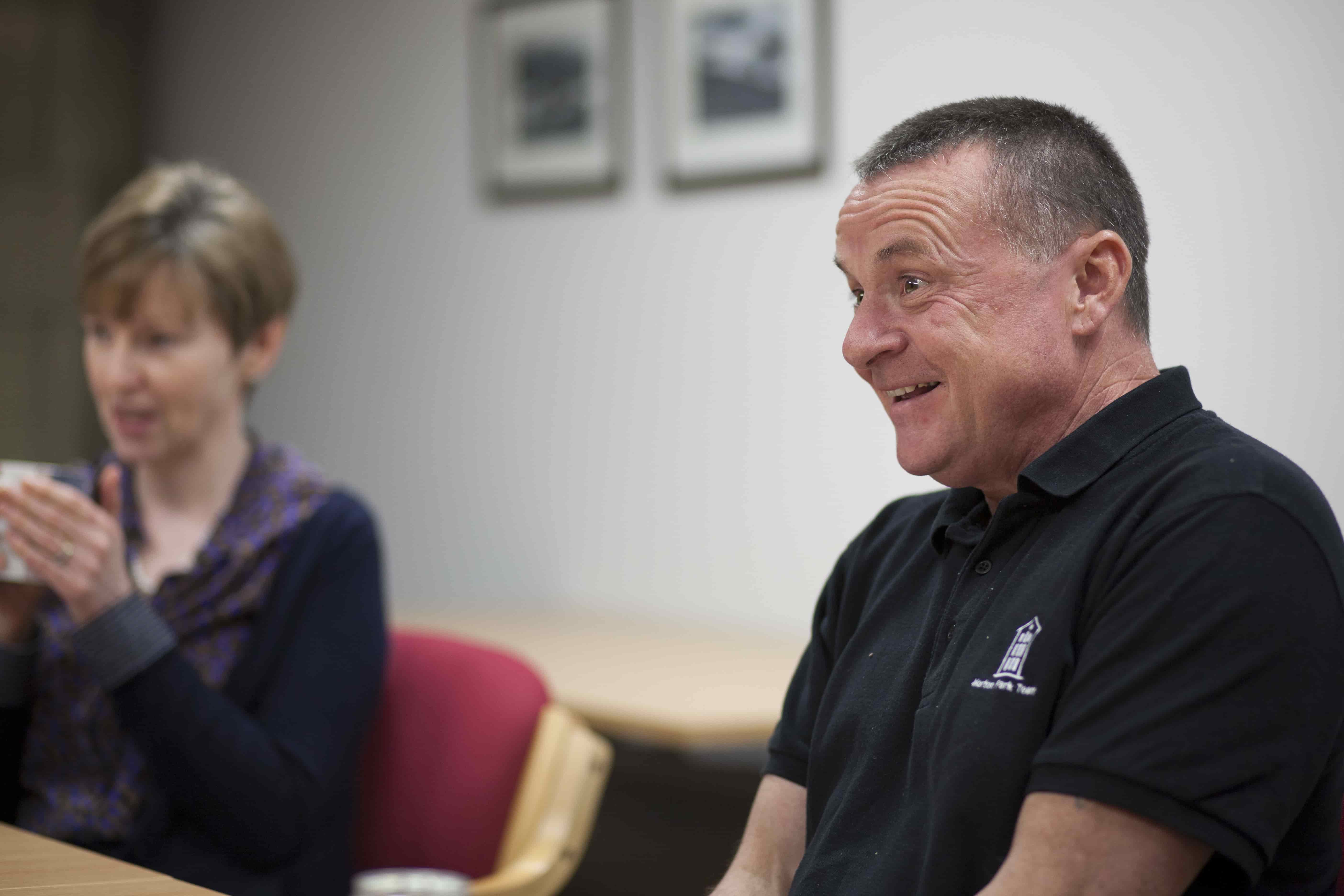 A member of the Albion Trust Team smiles while listening to someone in a conversation.