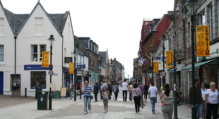 People walking along a high street in Scotland.