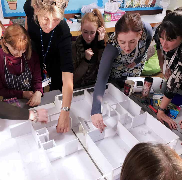  Teachers discussing a model floorplan of their school during a Tests of Change workshop and shifting walls around the walls.