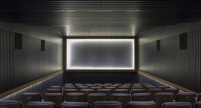 A dark auditorium in a cinema with a screen lit up with light around its edges.