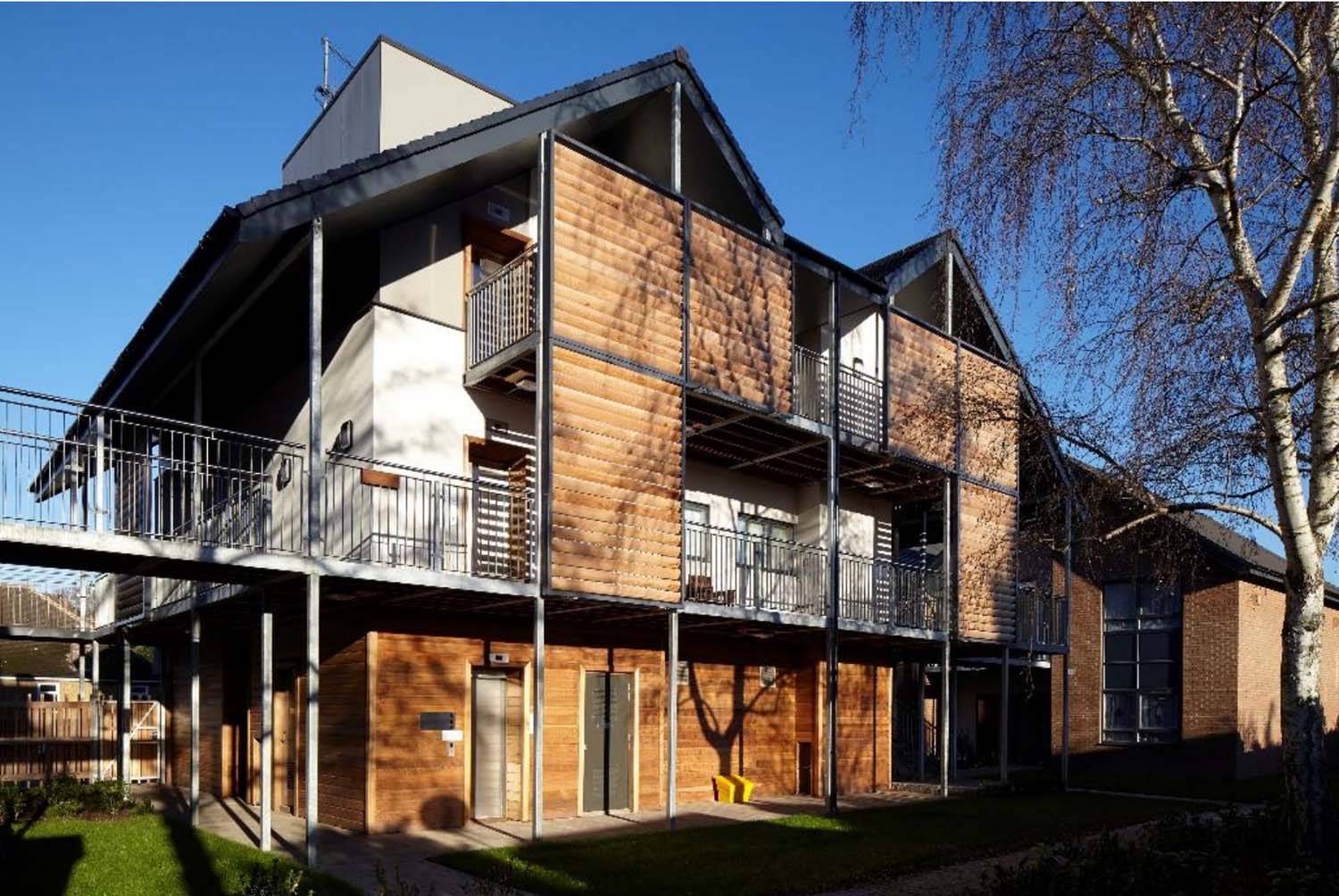 An exterior view of a three-storey apartment at Castlemain Court with some balconies covered with horizontal wood slats.