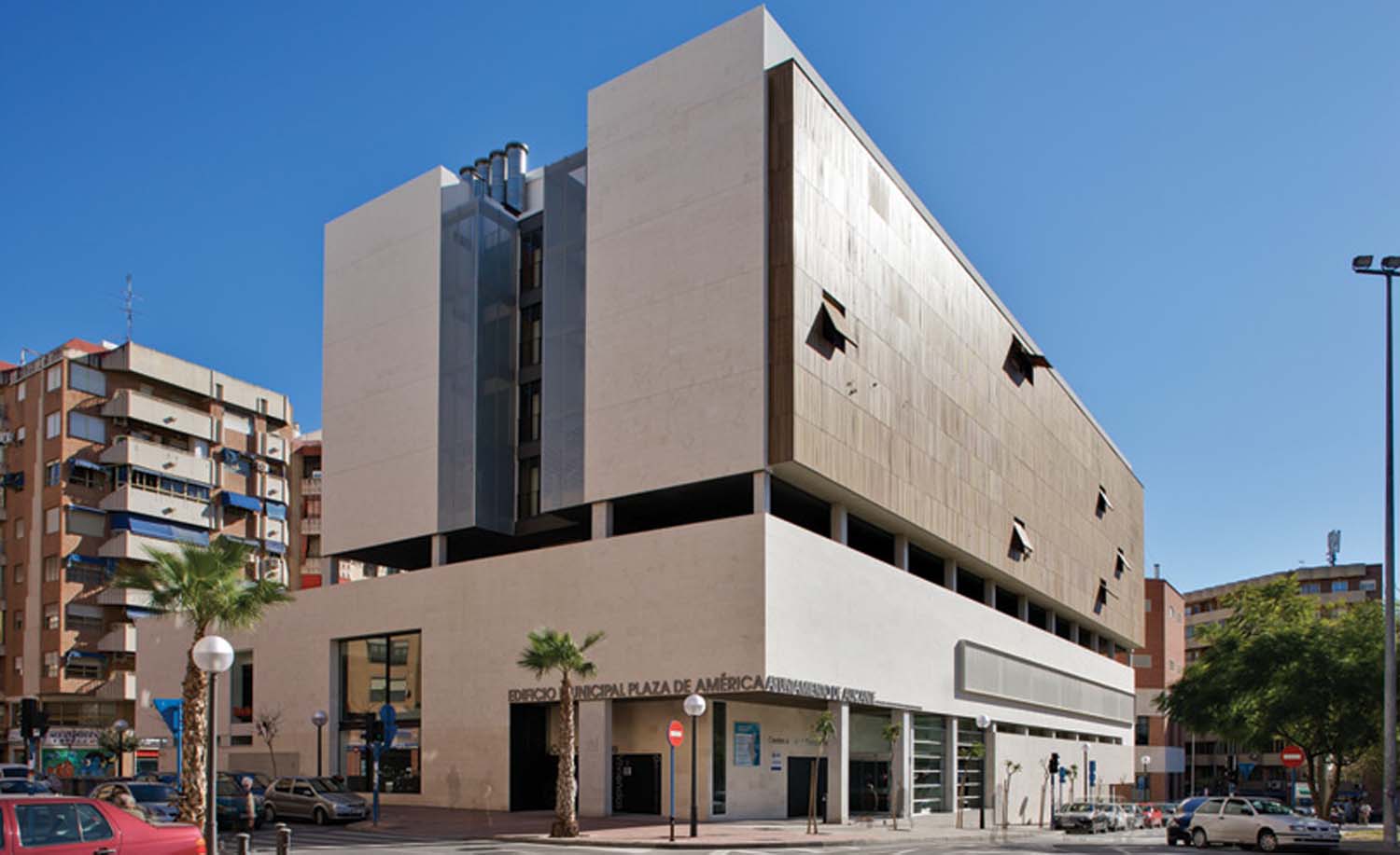 The entire Plaza De America building has white coloured exterior walls except for one pale brown wooden façade on one side of the structure.