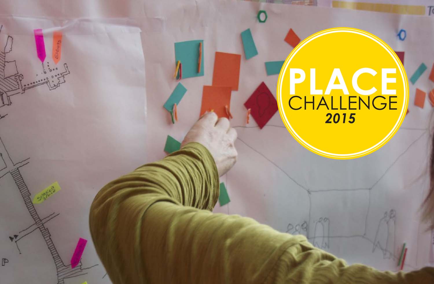 A close up image of a hand adding coloured notes to a white sheet of paper with a yellow circle with the words Place Challenge 2015 written on it