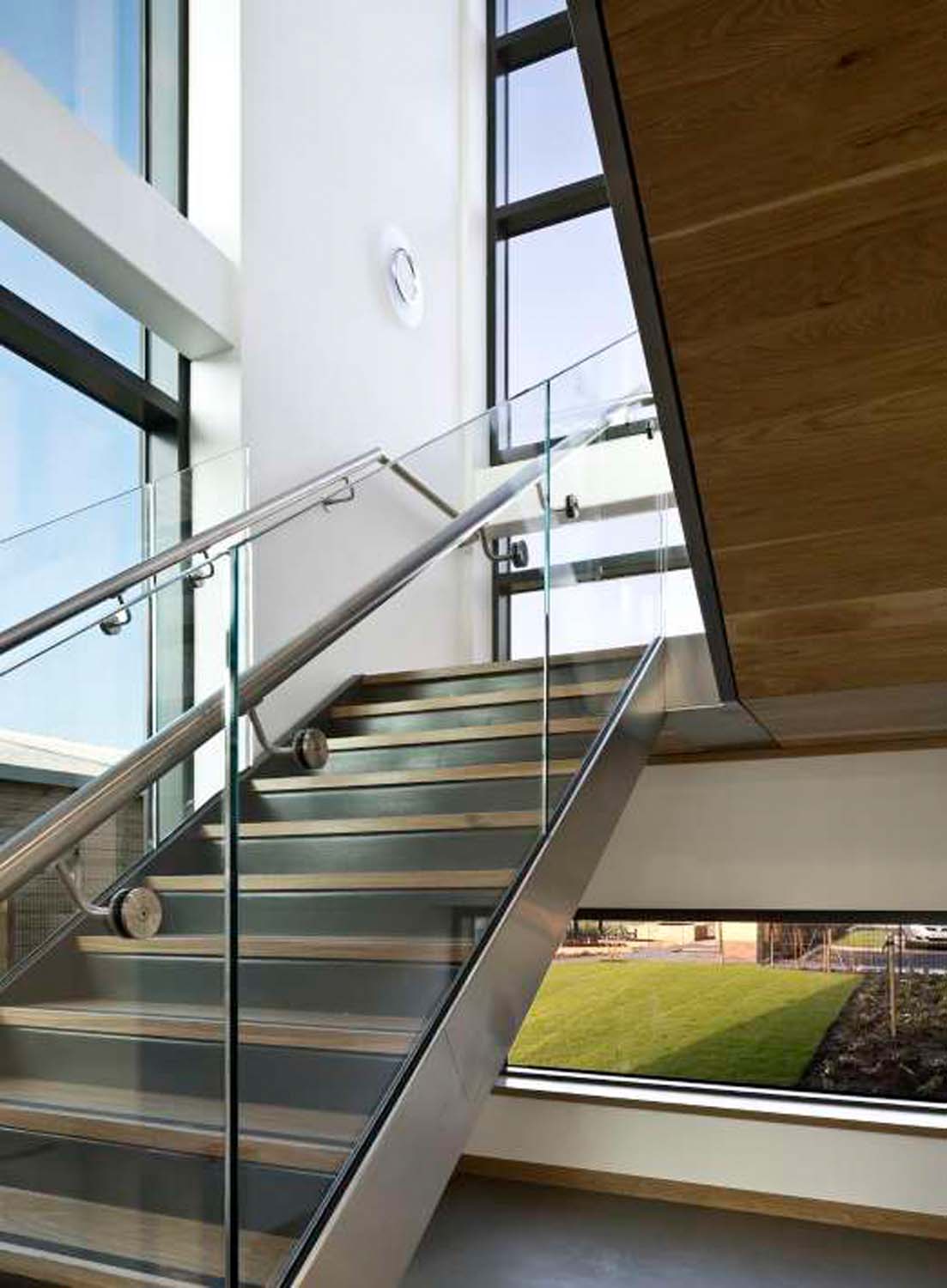 A photograph of a stair case which features a number of windows with a view into green space outdoors