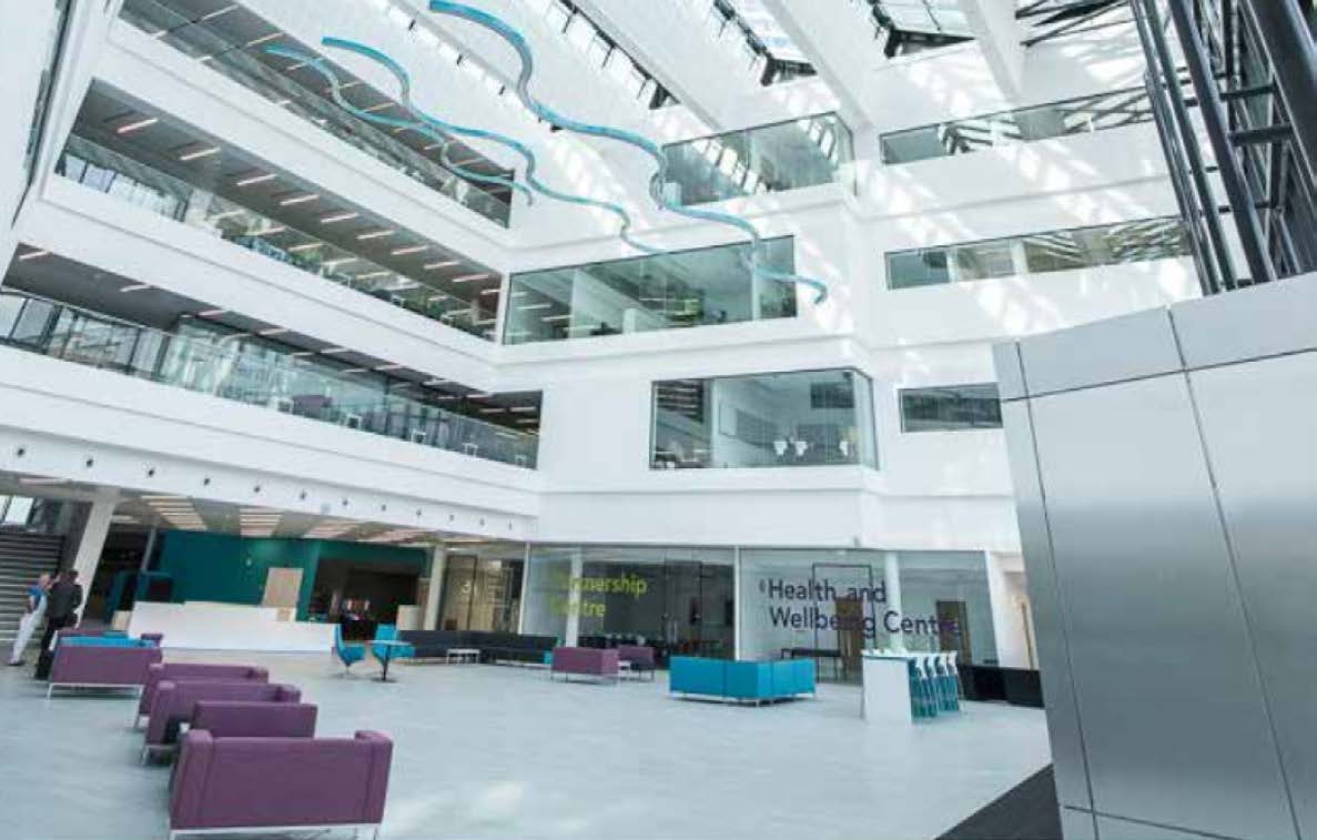 Snake-like light fixtures across Ayrshire College's bright atrium space. There are learning and office spaces arranged around the atrium.