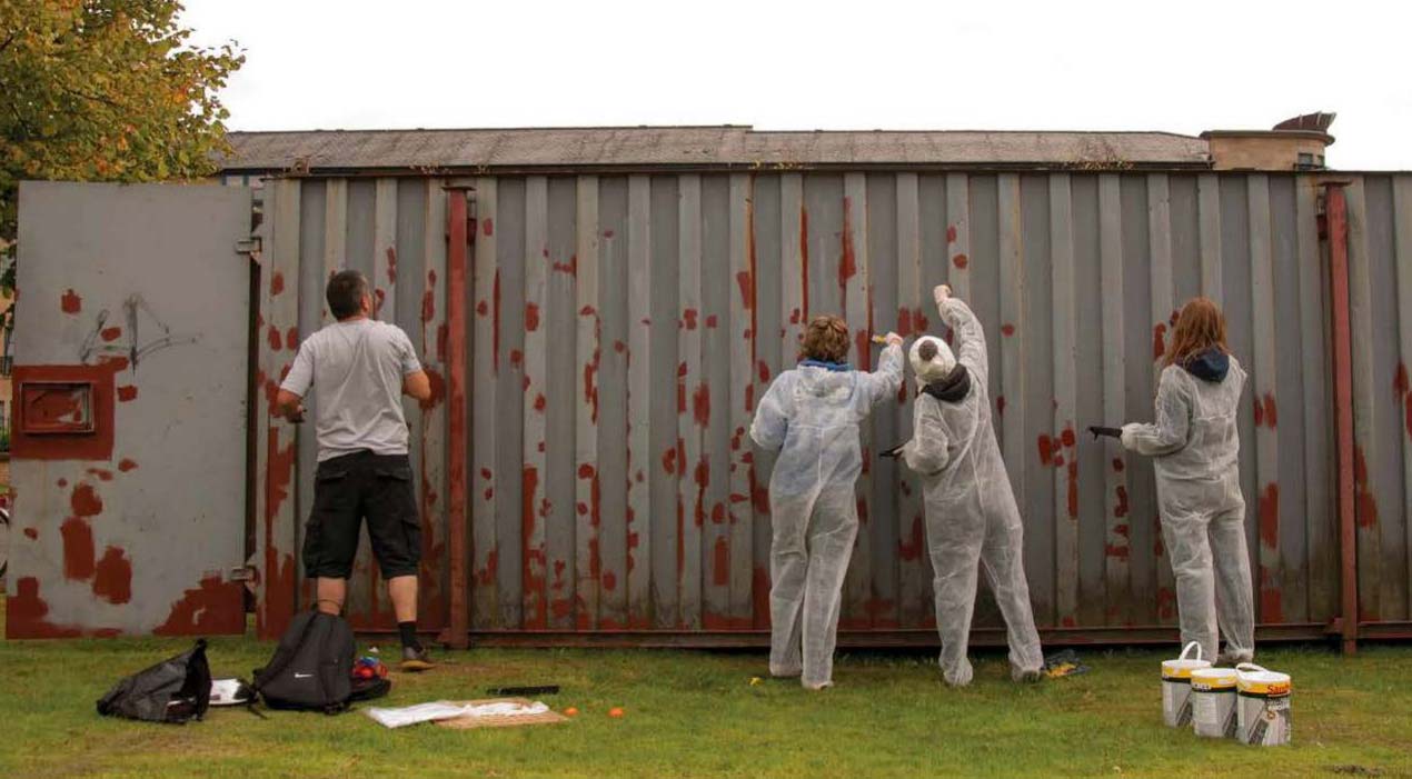 A group of people painting a grey container at the University of Strathclyde's Mobileland Stalled Spaces project.