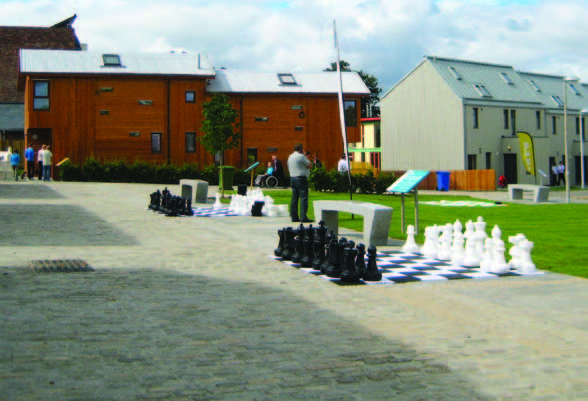 Two large outdoor chess sets placed on a pavement at the Scotland's Housing Expo with houses in the background.