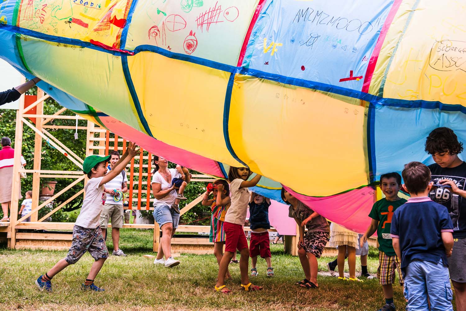 A group of young children play underneath a multi coloured inflatable object.