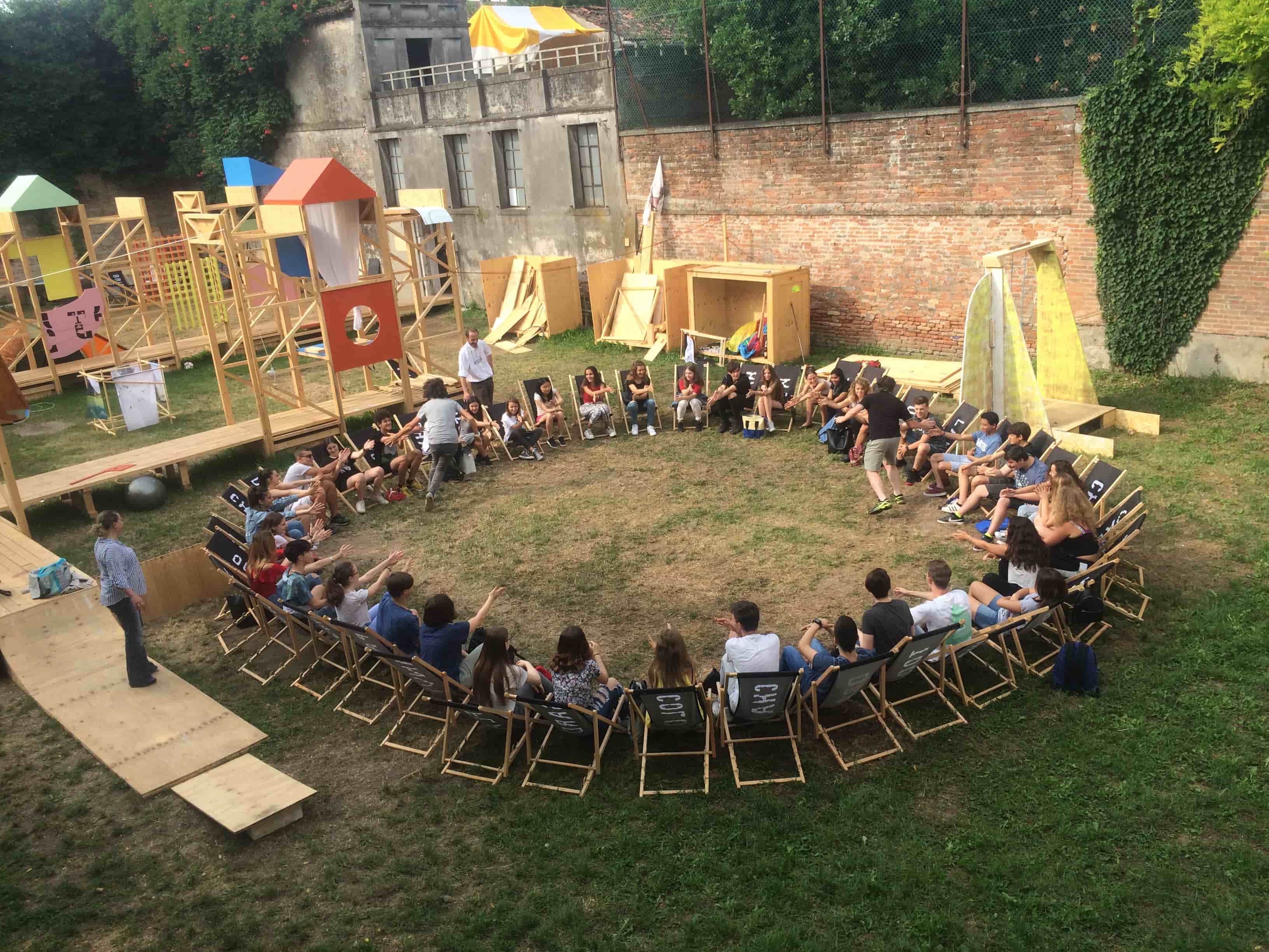 About 40 people are sitting in deckchairs in a circle and playing a game in The Happenstance’s garden venue.
