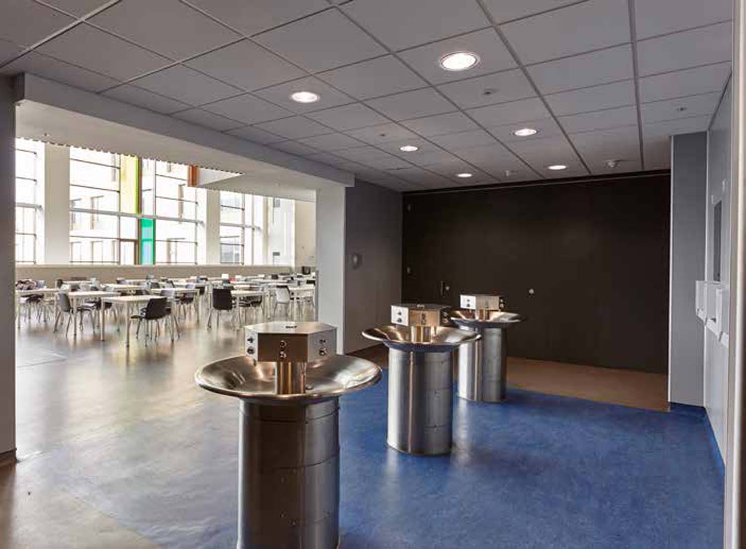 School toilet facilities connected to the main social space through a large opening on the wall. They are lit by natural light.