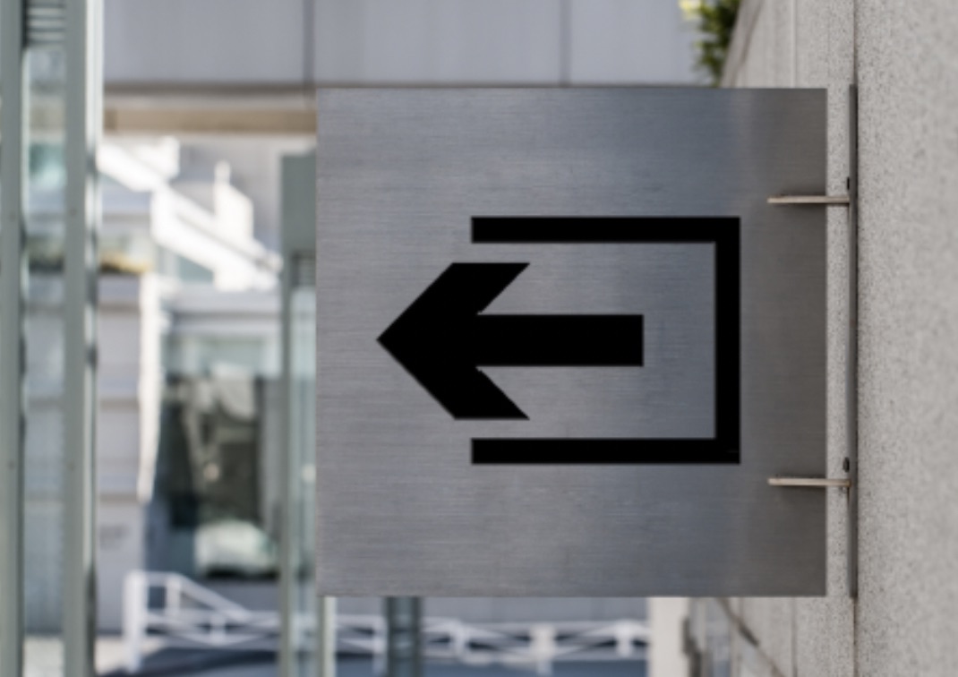 An exit symbol on a grey metal plaque.