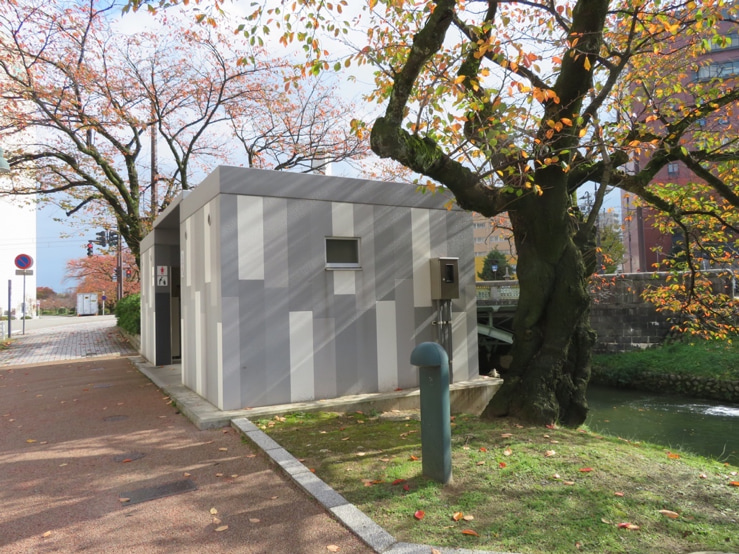 A cube shaped toilet facilities coloured with rectangular shades of grey paint in Toyama.