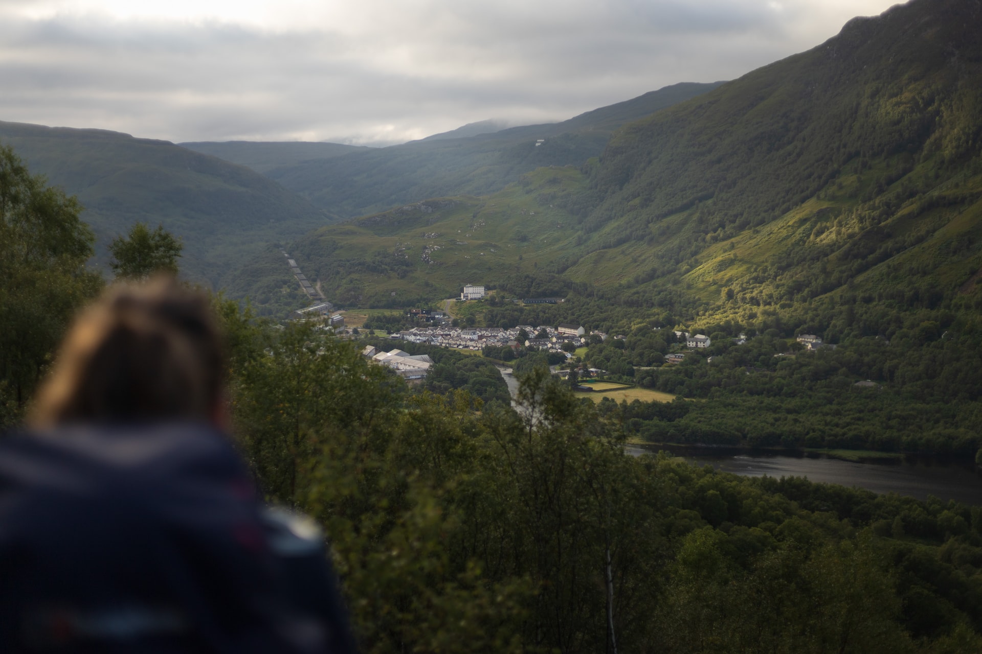 A hiker looks down at Glencoe Town from a distance.