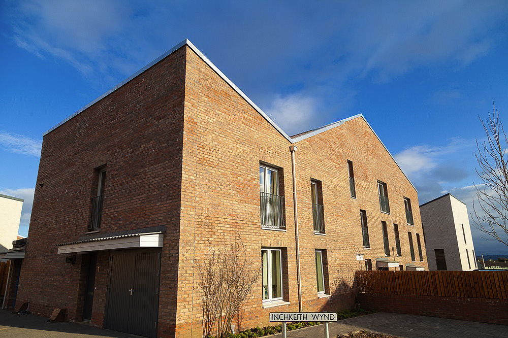 A red brick home in Fraser Avenue on a sunny day. The street sign reads: “Inchkeith Wynd”.